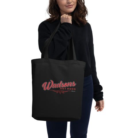 Woman holding up a black tote back with the words Wadsons Hot Rods in red writing and red pin stripping under. 